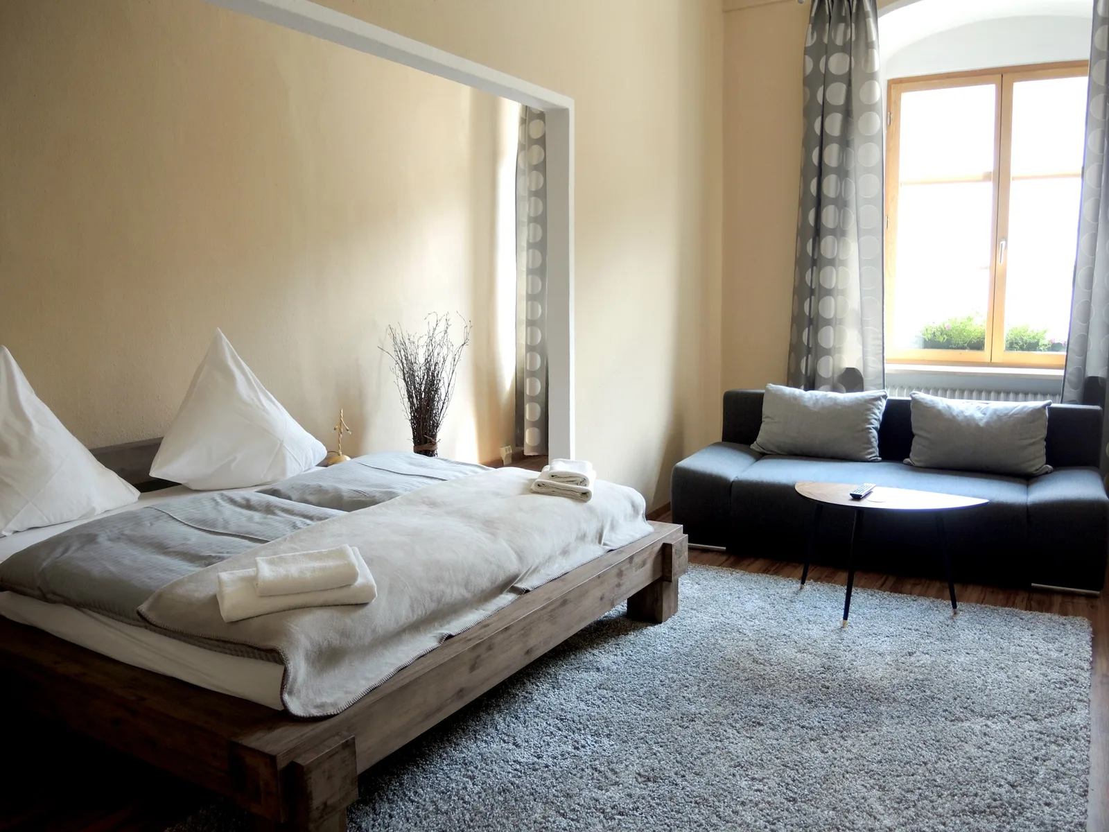 Großes Doppelzimmer mit Massivholzbett, Sofa und Fenster zum Hauptplatz